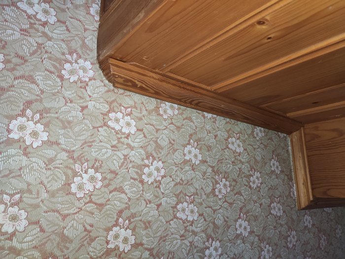 Ytterhörn av en trätrappa som möter en blommig tapetserad vägg.