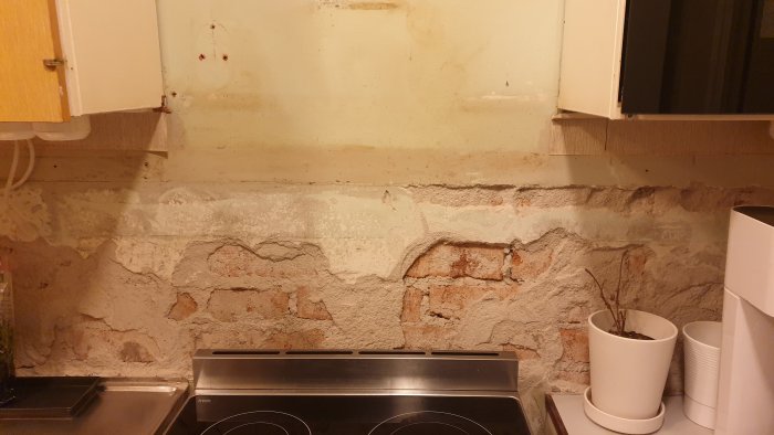 Kök med bortrivet kakel och synliga tegelväggar efter asbestsanering.
