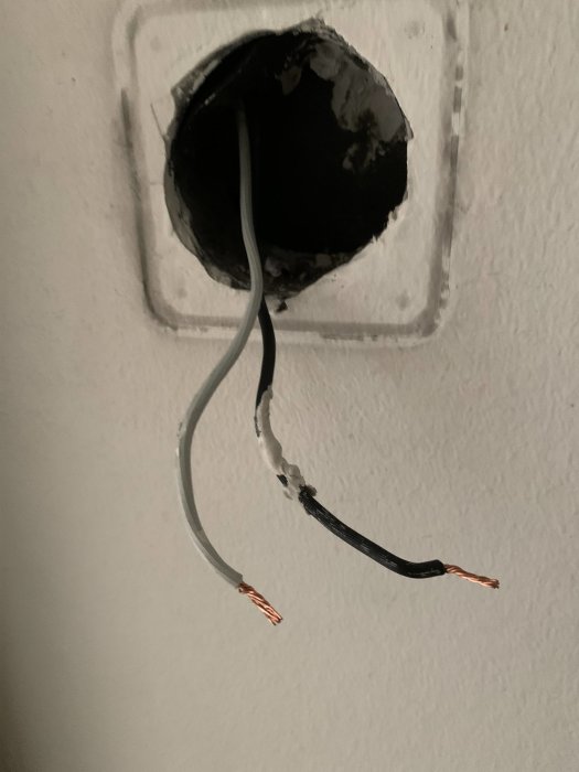 Öppen vägguttagshållning med två frilagda elektriska kablar redo för anslutning till ny strömbrytare.