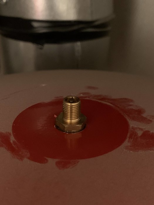 Ventil på toppen av en vattentank omgiven av en röd cirkel, eventuell lufttillförsel för tryckjustering.