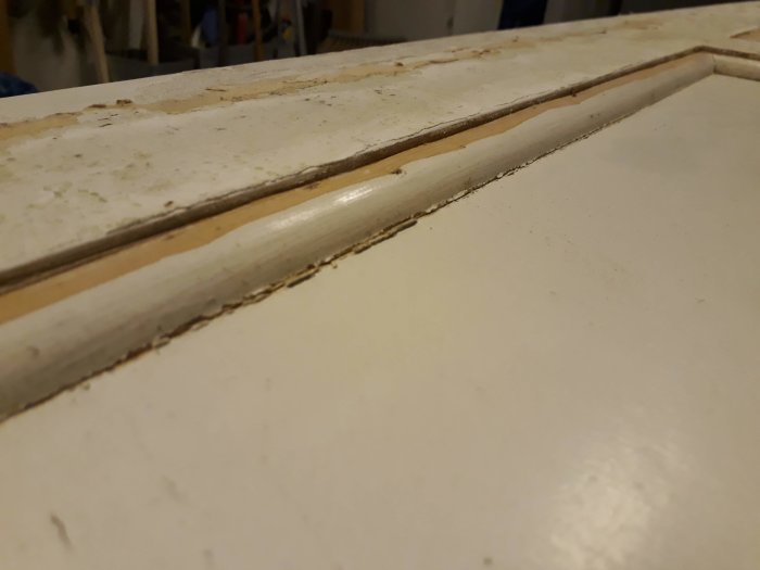 Närbild på en masonitklädd spegeldörr med borttagna kvartsstavar och synliga spikmärken.