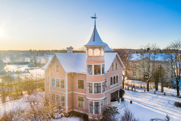 Rosa hus med torn från 1896 i vintersol, täckt av snö, i Söderhamn.