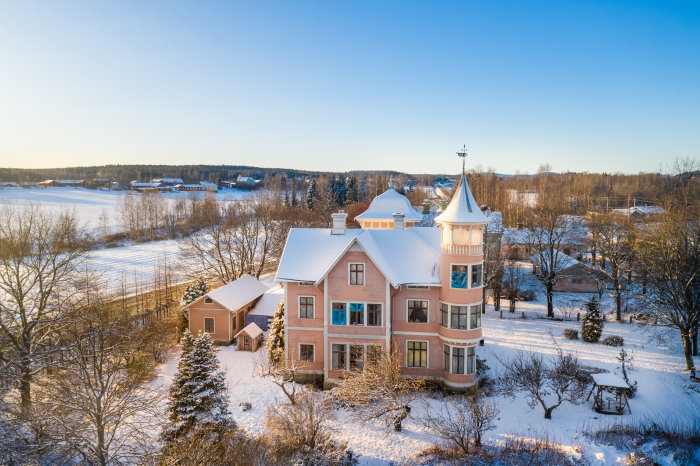 Vintage rosa målad villa med torn byggd 1896 i ett snötäckt landskap i Söderhamn.