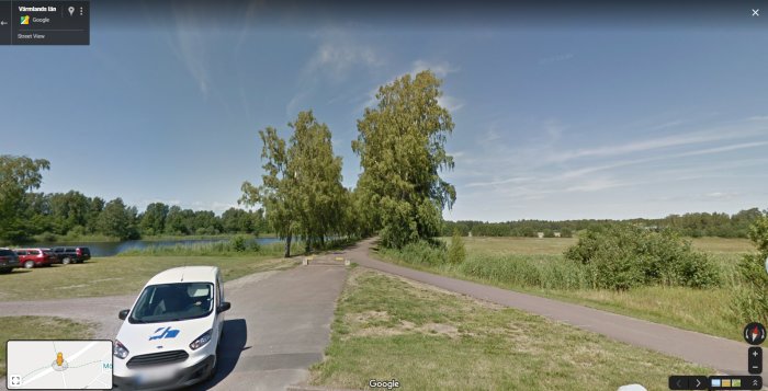 Cykelbana längs med grönområde och parkerade bilar vid en sjö, potentiell plats för småbåtshamn.