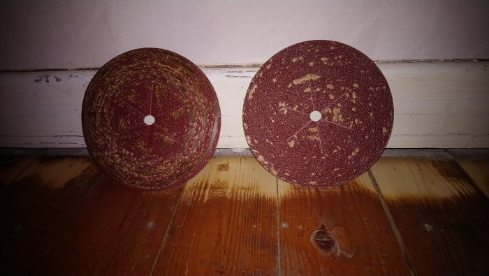 Två slippapper för golvslipning igensatta med sliprester, P80 till vänster och P36 till höger, på trägolv.