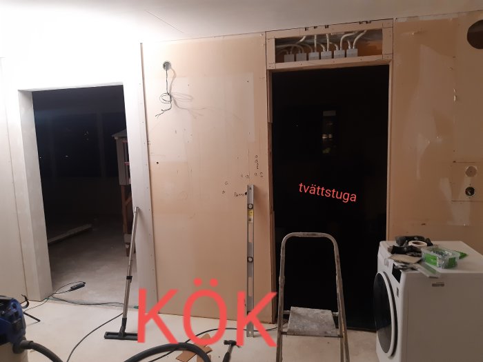 Renoveringsarbete med oöppnad vägg ovanför dörr visande synliga kopplingsdosor och gipsväggar.
