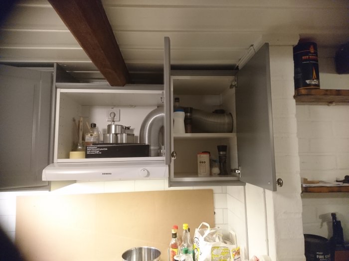 Köksfläkt installerad i skåp med slang ansluten till rör, möjlig fråga om ventilationseffektivitet.