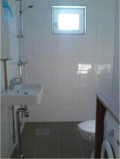 Renoverat badrum med nyinstallationer inklusive toalett, handfat, dusch och tvättmaskin.