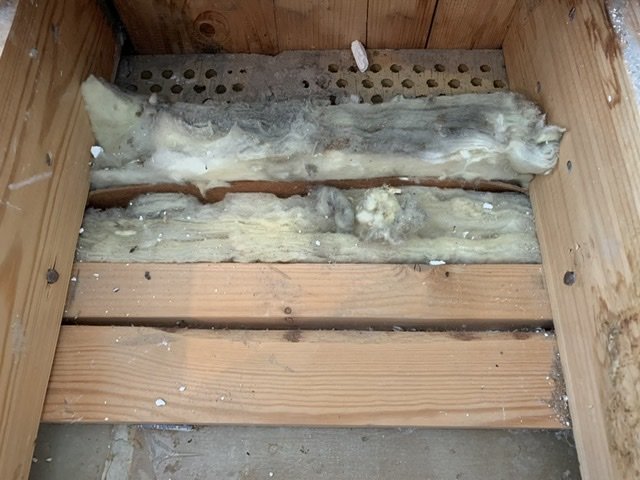 Öppet golvbjälklag med synlig mineralullsisolering och träreglar utan luftspalt.