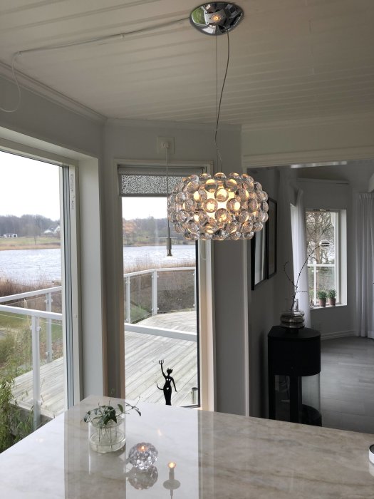 Nyupphängd Foscarini Caboche Picola pendellampa i köket, med tända lampor och detaljerad reflektion.