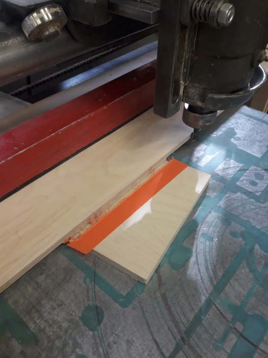 Träjigg i en sinkmaskin används för precisionsspårfräsning i plywood med orange tejp som urslagsskydd.