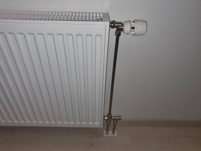 En vit Purmo radiator med en Danfoss RA-N ventil och numrerade förinställningsring för kv-värden.