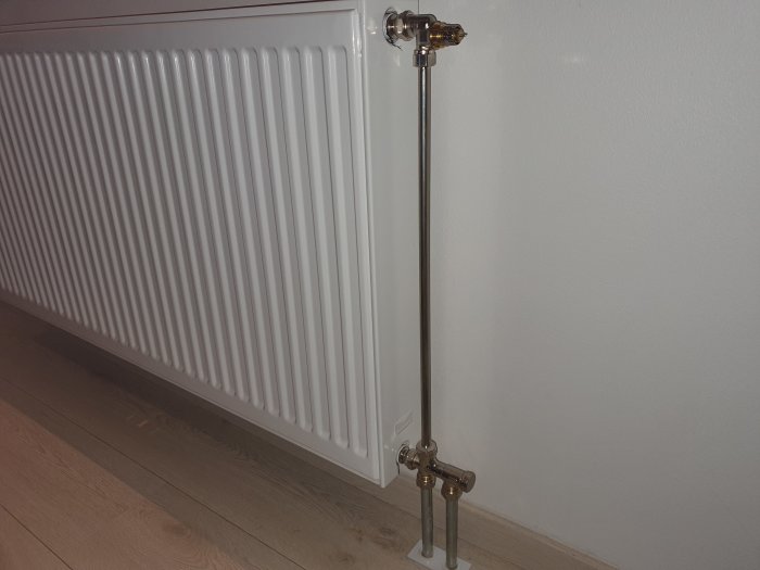 Purmo radiator med Danfoss RA-N ventil och numrerad ring förinställning vid vit vägg.