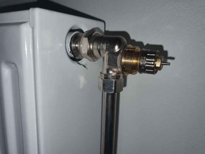 Danfoss RA-N radiatorventil med förinställningsring, monterad på en vit radiator med kopparanslutning.
