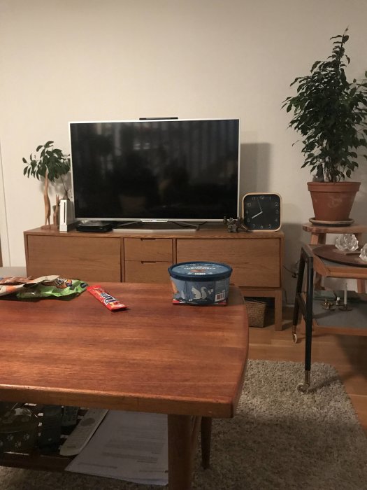 Rött teakbord med snacks framför TV och möbler i bakgrunden.