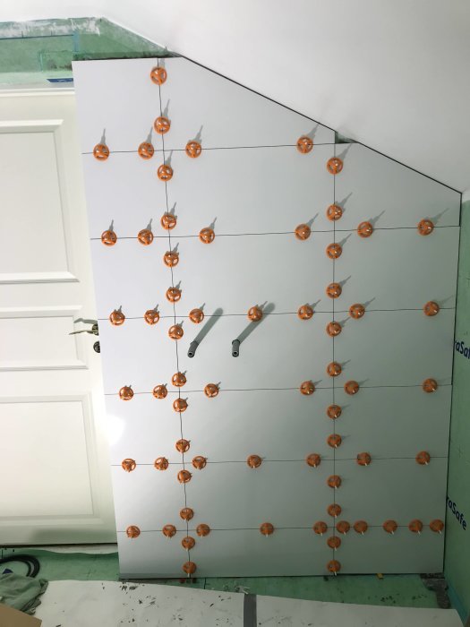 Kakelsättning med orange distanser misslyckades vid dörröverkant, ojämna plattor.