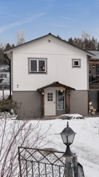 Husfasad med en befintlig smal entré i mitten, indikerar planerad plats för utbyggnad under ett framtida platt tak.