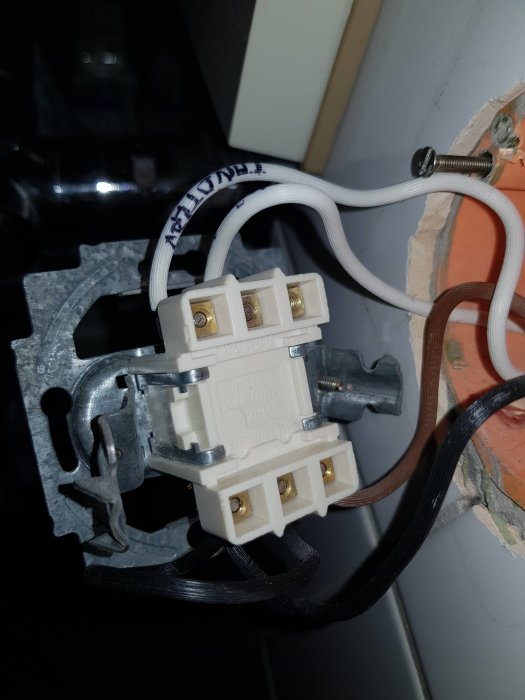 Dubbelkopplingsbrytare monterad i vägg med synliga kablar och skruvanslutningar.