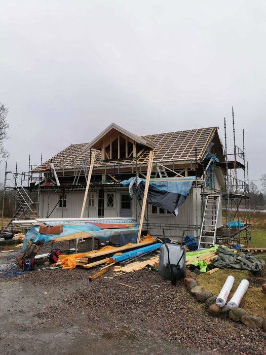 Ett hus under renovering med träspikar och byggställningar, innan tegelfasaden påbörjats.