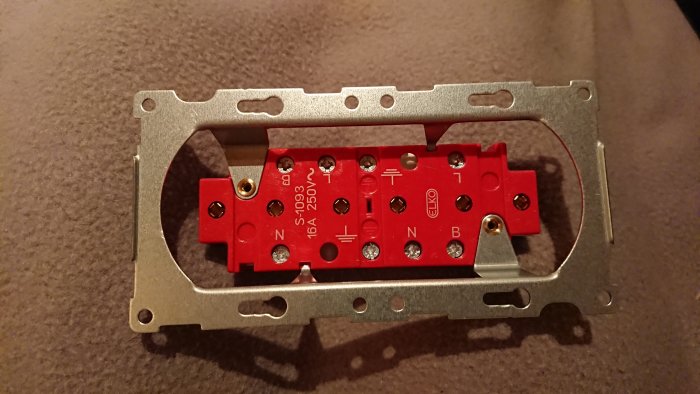 Elko 3-vägsuttag med öppen röd plastkropp som visar plintar märkta med B för ev. vidarekoppling.