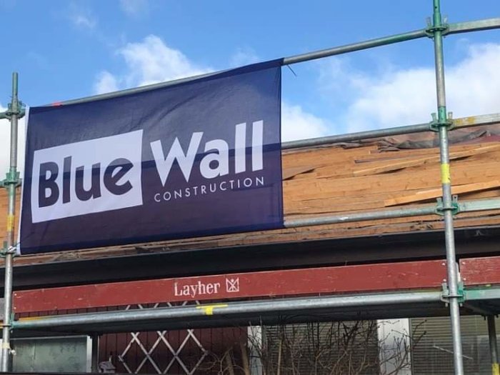 Blue Wall Construction banderoll på ställning vid byggarbetsplats.