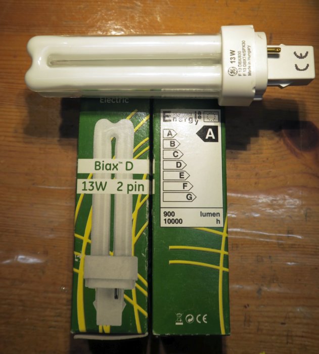 Compact fluorescent lamp and its packaging showing specifications labeled 13W and 2 pin.