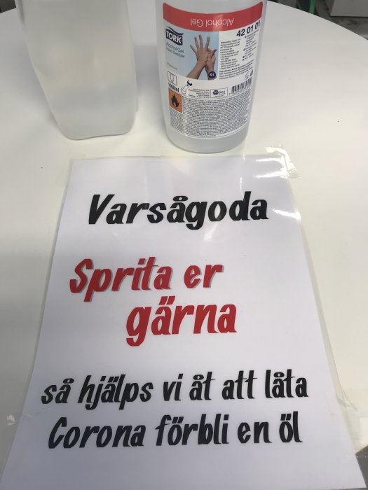 Skylt som uppmanar till handspritning med texten "Varsågoda Sprita er gärna så hjälps vi åt att låta Corona förbli en öl" och handspritflaska.