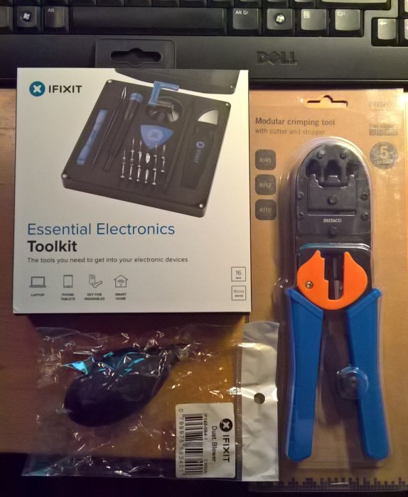 IFIXIT Essential Electronics Toolkit och en modular crimping tool på ett tangentbord.