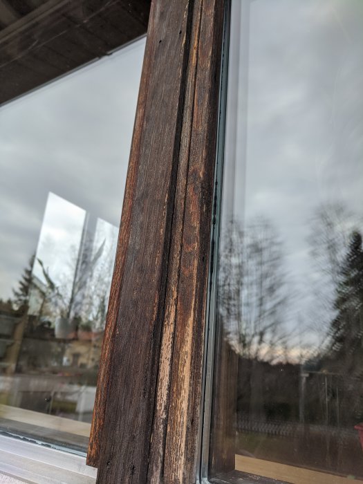Närbild av en väderbiten träfönsterkarm i behov av slipning och oljning.