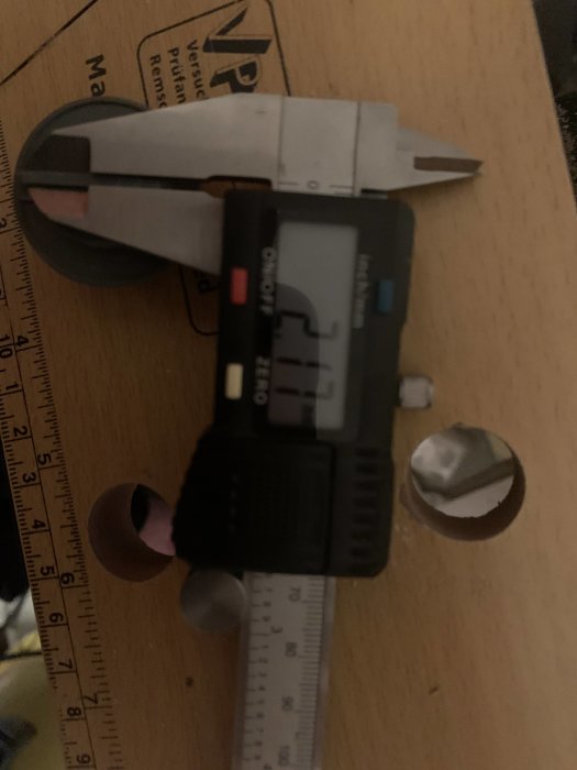Digital skjutmått som mäter en detalj med en linjal i bakgrunden.