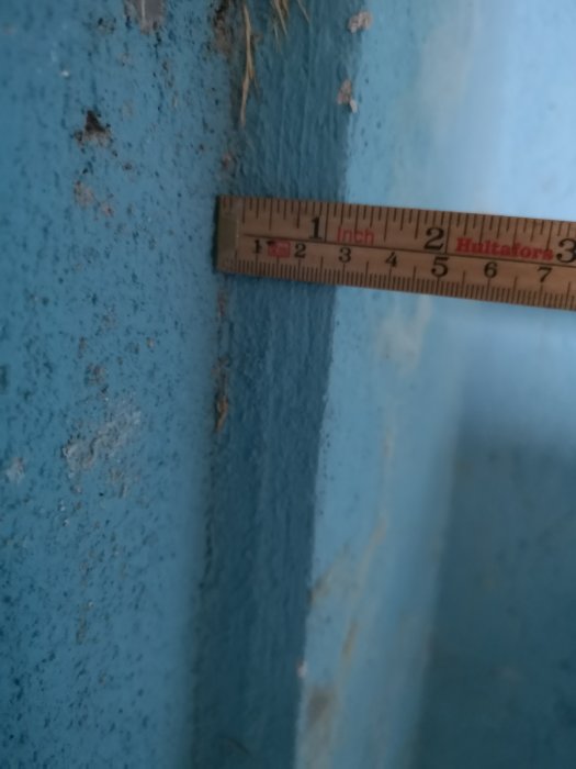 Tumstock mot blå vägg där en tidigare garageport varit, visar 3 cm djup skillnad i puts.