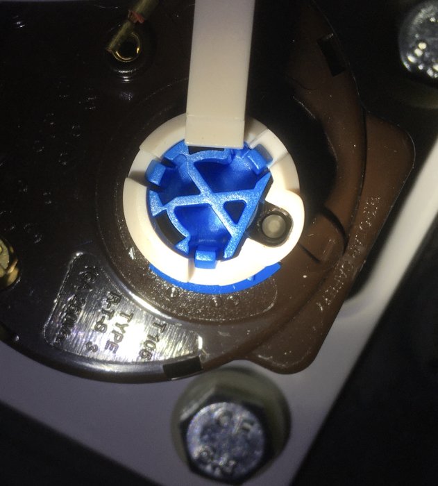 Närbild av en blå strömställare i en apparat, omgiven av skruvar och kablar.