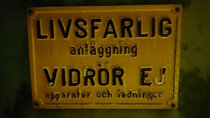 Gammal gjuten aluminiumskylt med upphöjda bokstäver 'LIVSFARLIG anläggning VIDRÖR EJ'.