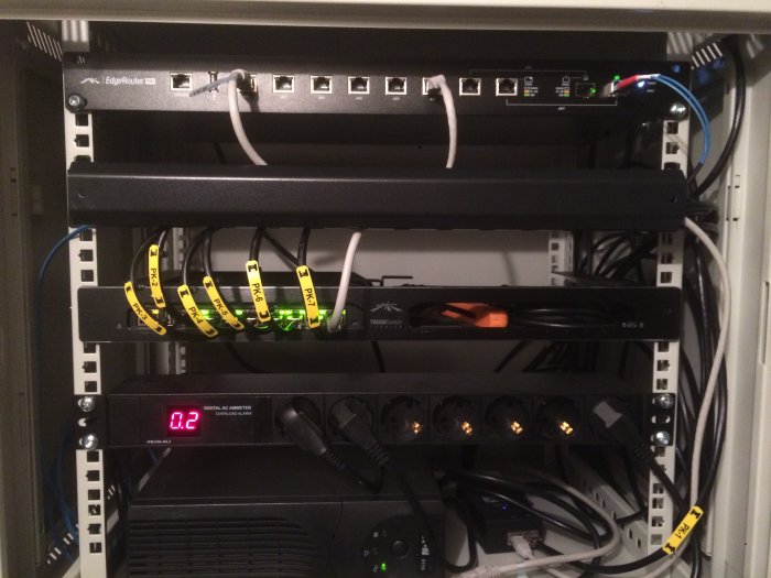 Nätverksskåp med router, switchar och märkta kablar som visar en ren installation.