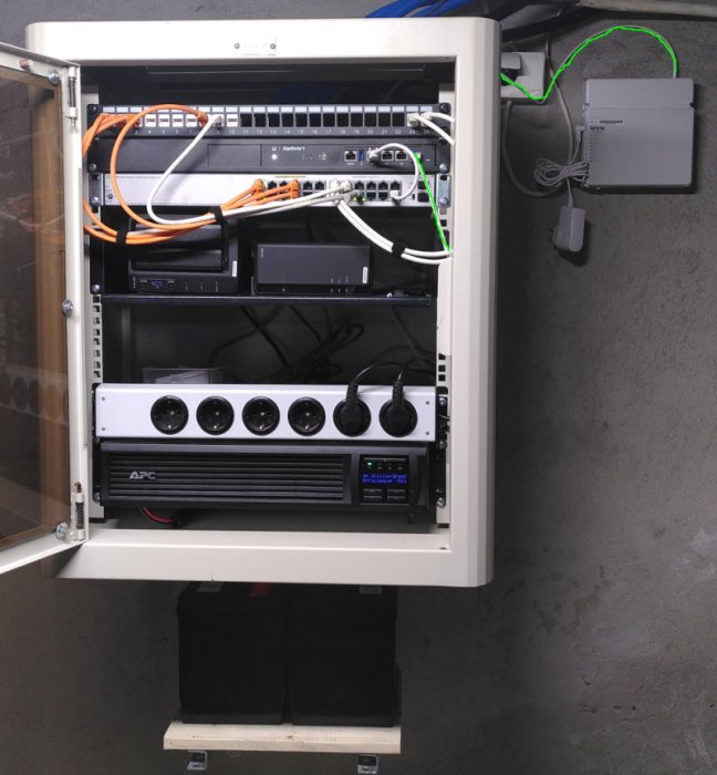 Nätverksskåp med utrustning och fiberkabel markerat med grönt, UPS och router ingår.