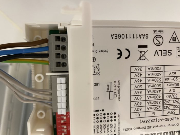 Närbild av ett elektriskt drivdon med fyra kablar anslutna till klämmorna och etikettinstruktioner.