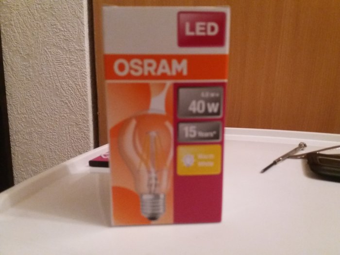 OSRAM LED-lampa förpackning som anger 15 watt användning motsvarar 40 watt glödljus, suddigt i förgrunden.