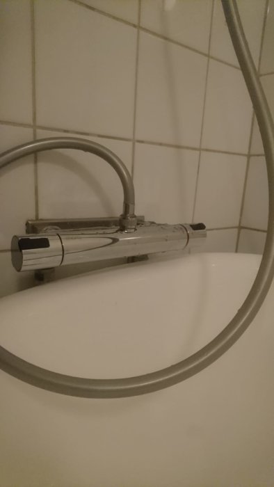 Nyinstallerad Mora Cera T4 blandare med utlopp uppåt på vit handfatkant, omgiven av kakelvägg och duschslang.