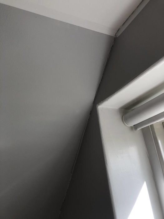 Spricka längs vinkel där vägg möter tak bredvid ett fönster, indikerar rörelse eller sättning i huset.
