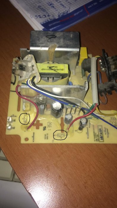 Elektronisk kretskort med transformator, kondensatorer och lödade sladdar, eventuellt från en apparat.