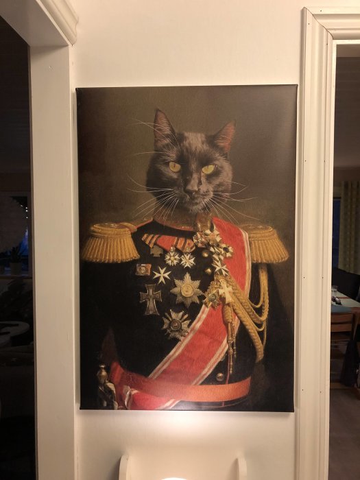 Stor porträttbild på en katt med ett människokropp i uniform som hänger på en vägg.