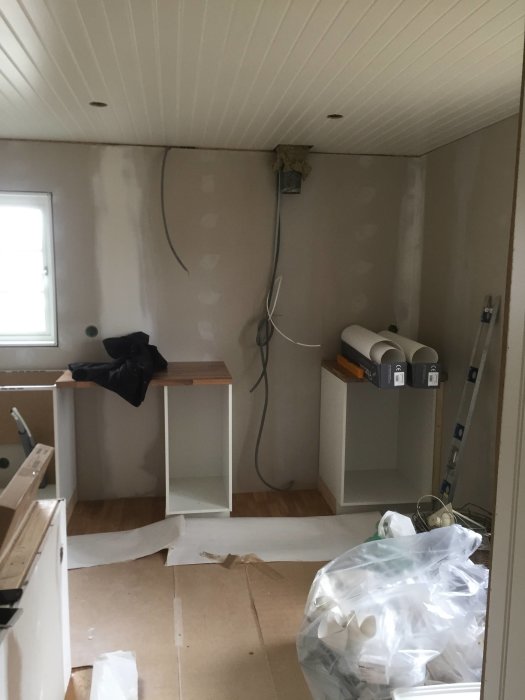 Kök under renovering med nya vita underskåpsstommar och synliga elförberedelser på väggen.