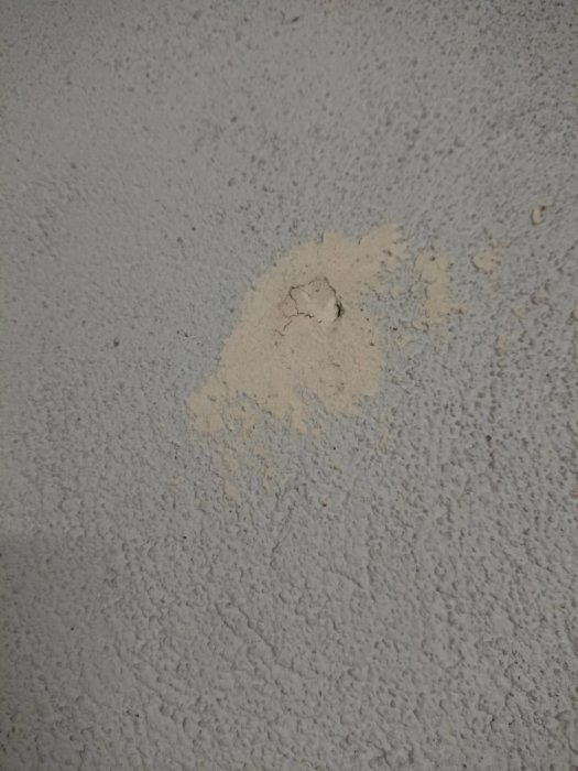 Närheten av en vägg med en område av spackel eller fyllmedel som är delvis bortskrapat och exponerar poröst material under.