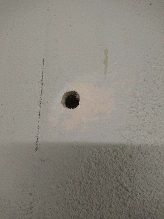 Porös vägg med en spacklad hålighet och en vertikal spricka, tecken på möjlig putsreparation.