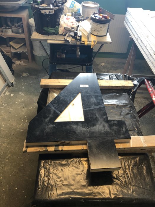 Stor nummer 4 i svart akryl på en arbetsbänk, med förarbete för att sätta in LED-belysning i ett byggprojekt.