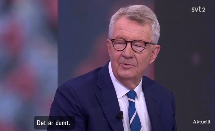 Man i kostym med glasögon som blinkar på TV-programmet Aktuellt, textremsa "Det är dumt.