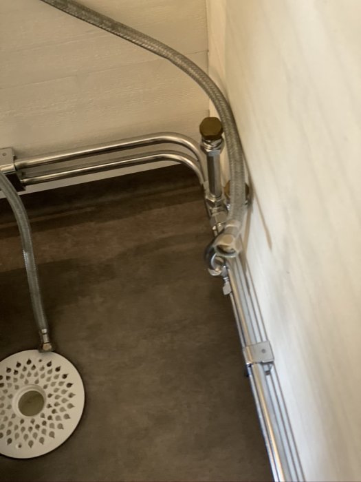 Vattenledningar och kopplingar längs en vägg i ett Attefallshus, förberedda för duschkabininstallation.