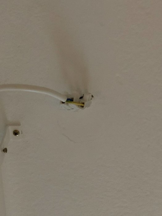 Kabel ansluten till en öppen elinstallation på en vit takyta, med spår av sot eller smuts runt installationspunkten.