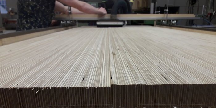 Frässläde i användning för att plana en bordsskiva av limmad plywood med synliga fanerkanter.