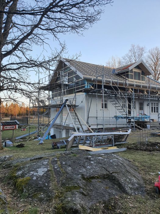 Hus under renovering med ställningar och tre nya fönster installerade.